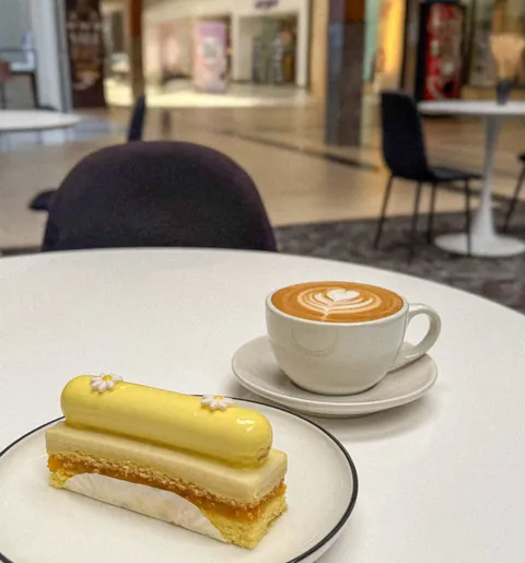 Latte and a glazed dessert at a café table inside Haywood Mall